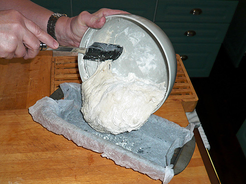 Scraping the bread dough into the greaseproof paper covered mold